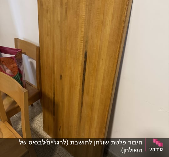 לוח עץ עומד ליד כיסא על רצפה